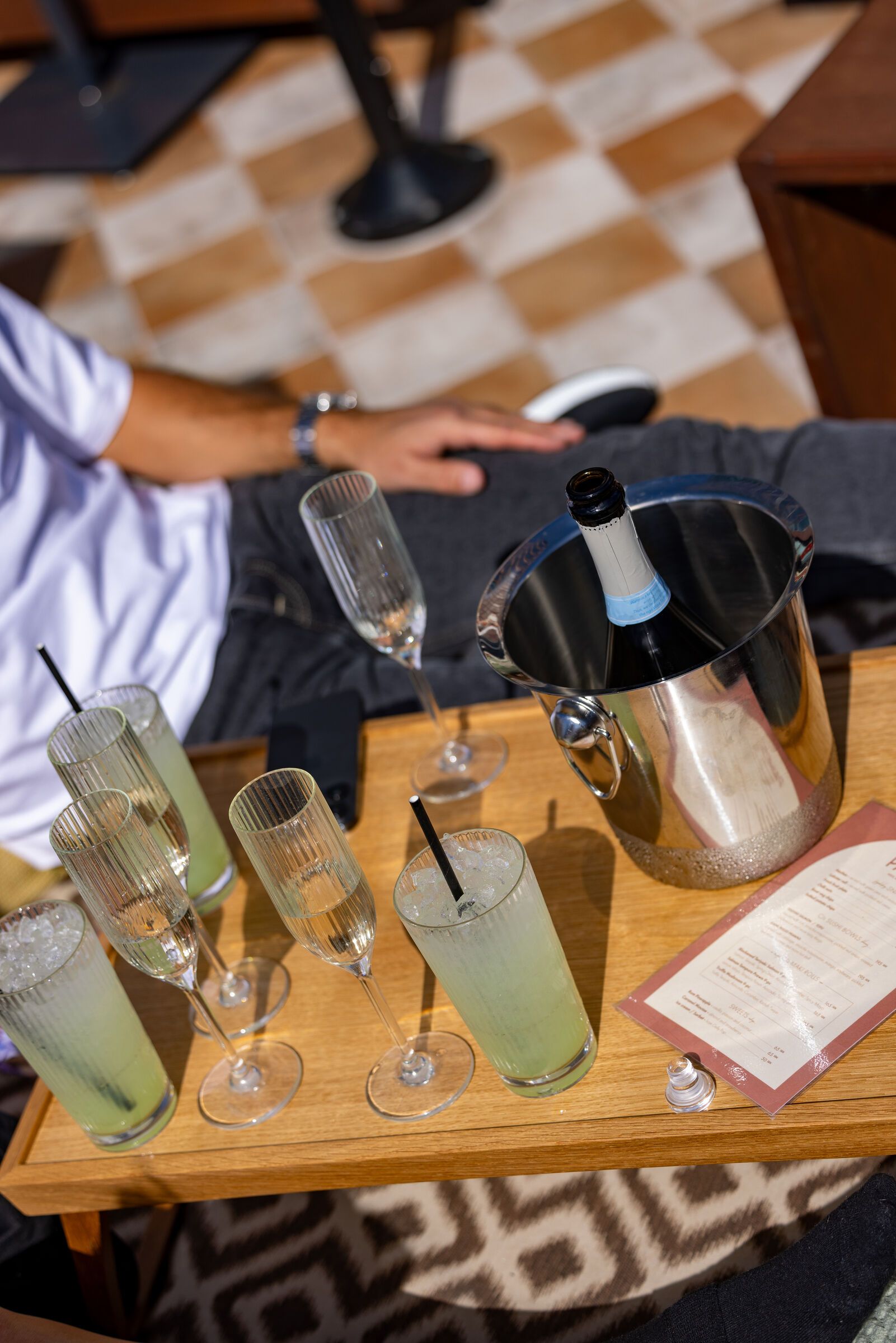Drycker i räfflade glas och champagneflöjter på ett träbord med en ishink.