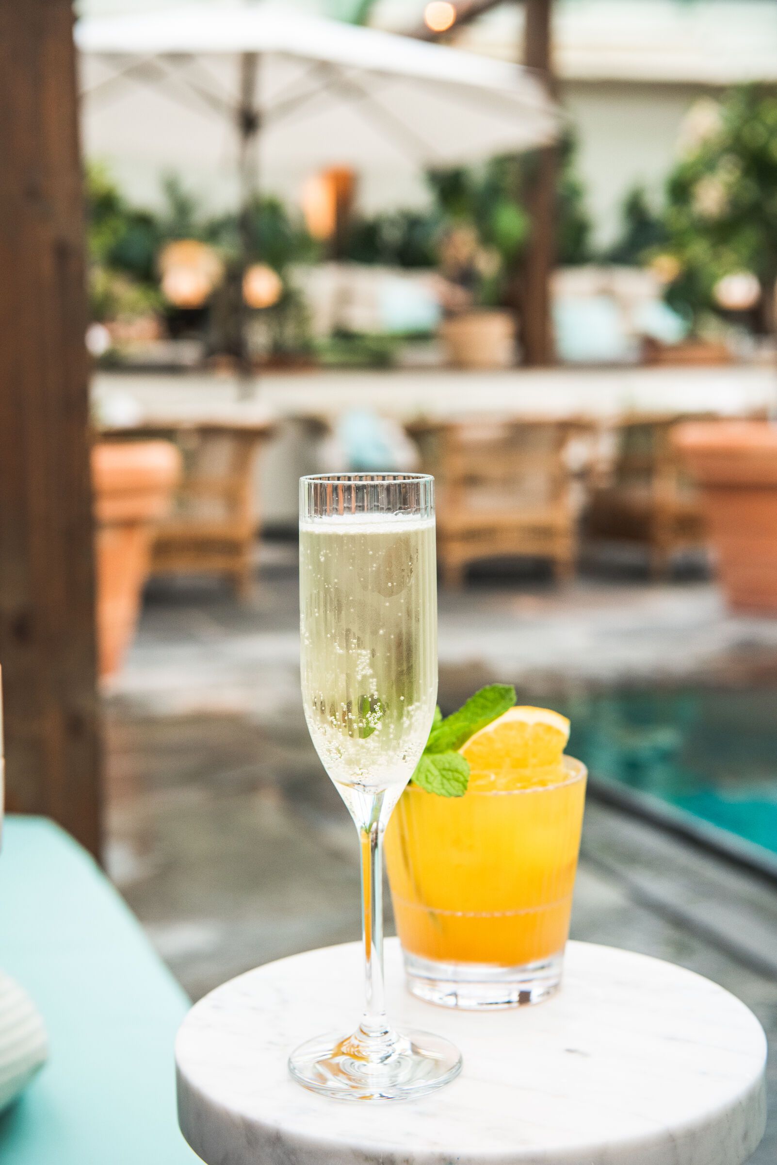 Champagneflöjt bredvid en orange cocktail i ett rocks-glas.