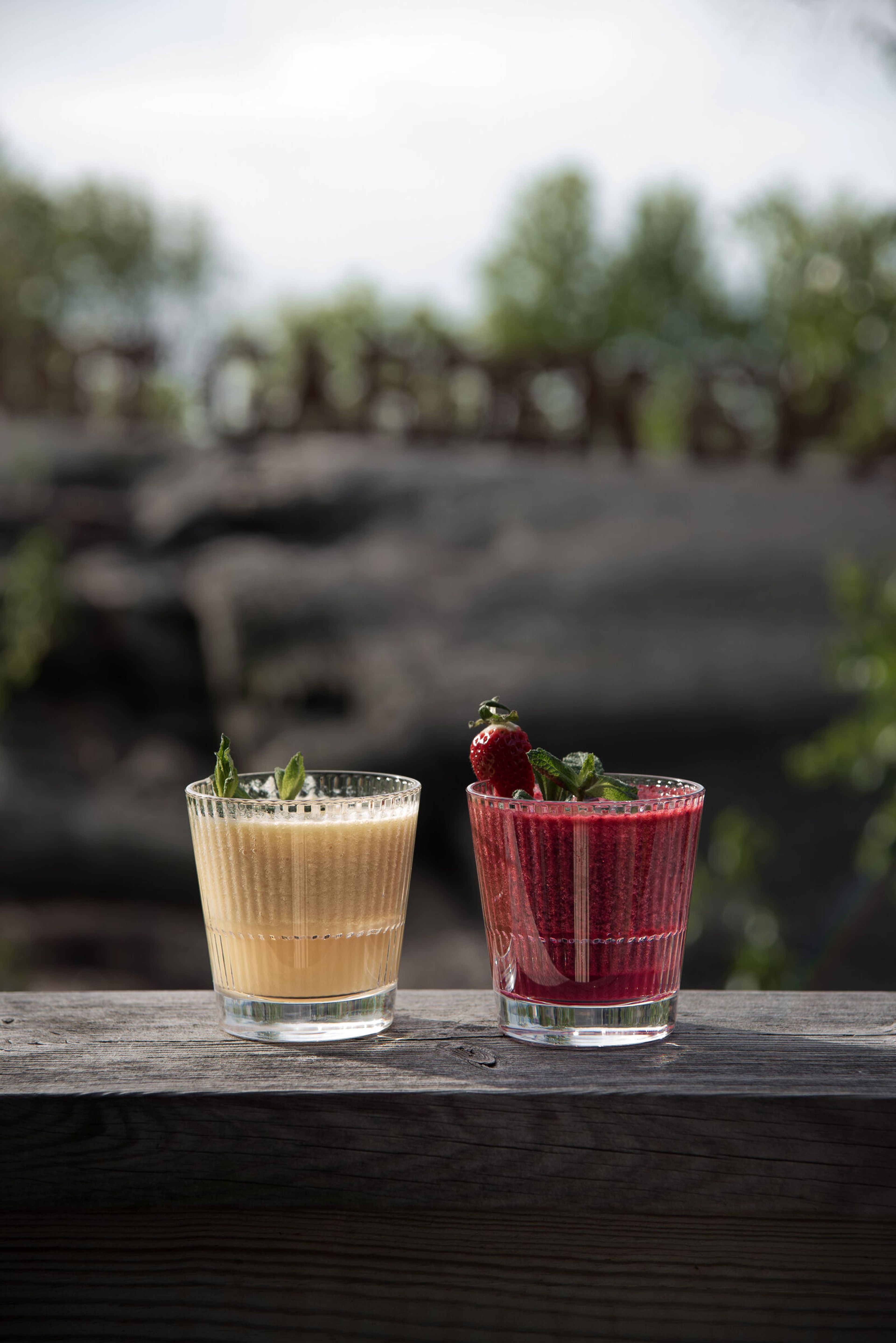 Två smoothies i rocks-glas på ett sidobord.
