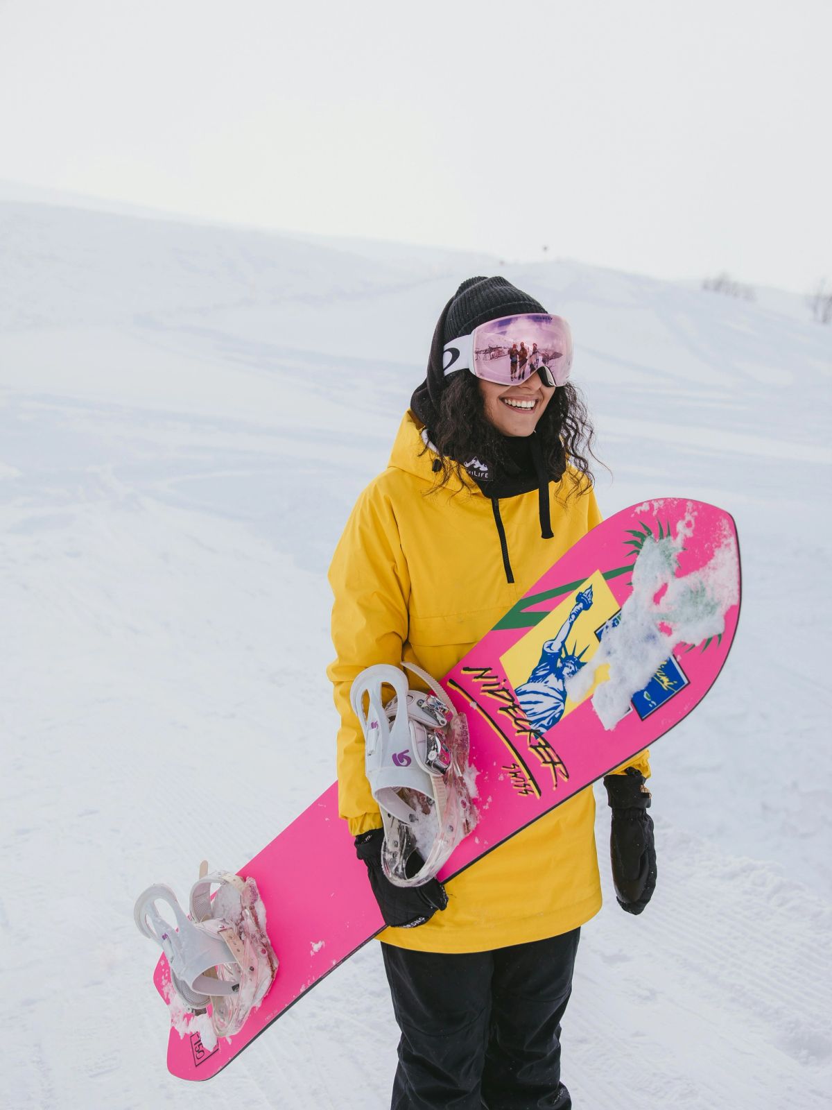 A woman holding a snowboard in snow