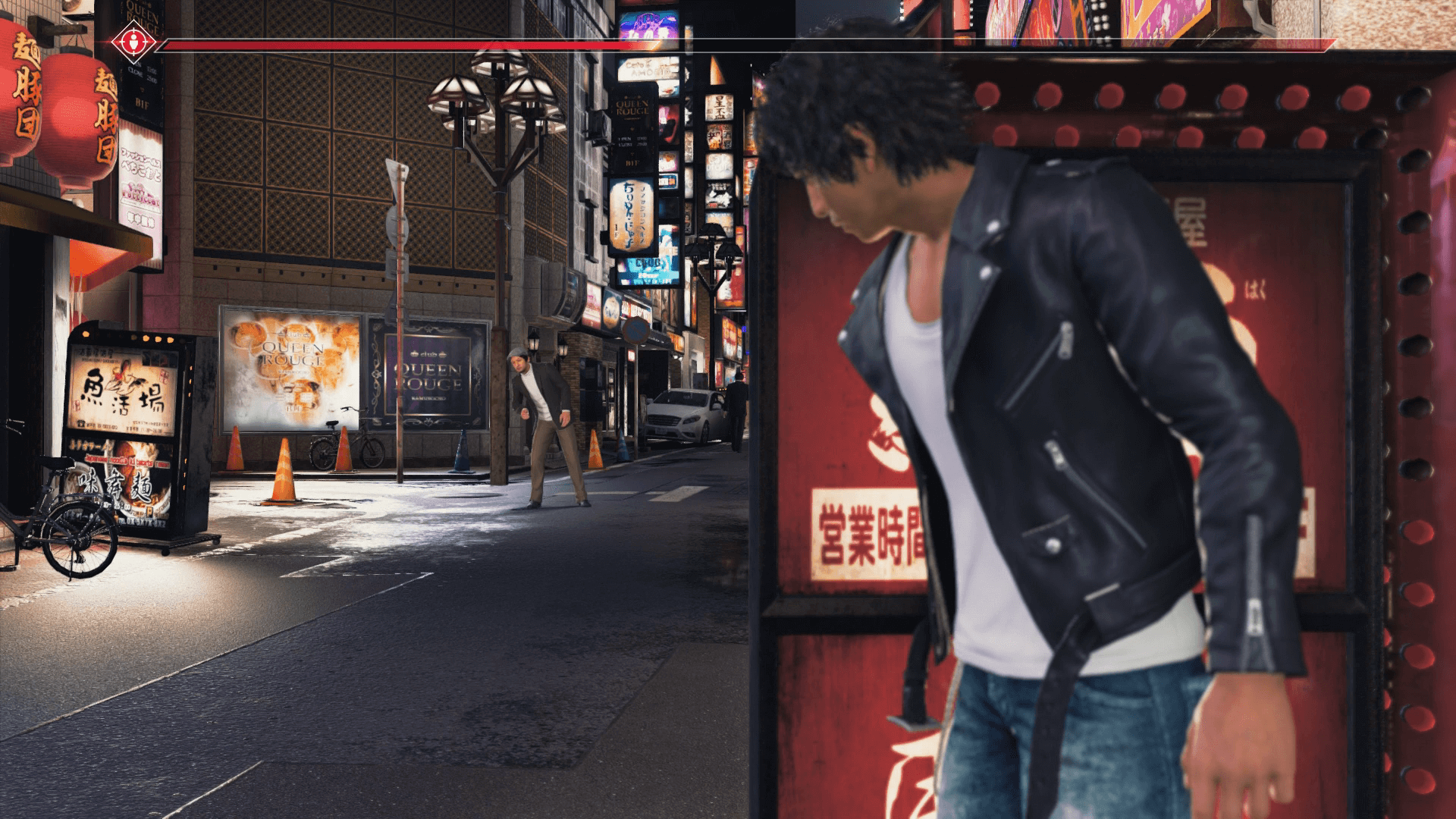 Yagami hides behind a red sign on a Kamurocho side street, watching a man further down the road, with a suspicion meter across the top of the screen