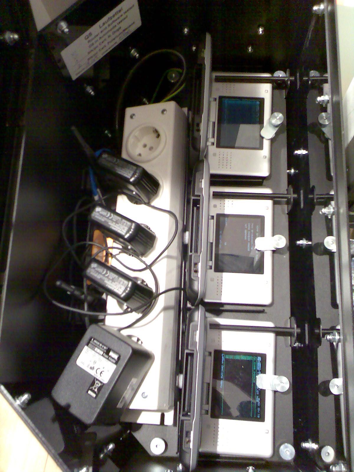 A Nintendo DS Download Station kiosk with several tethered DS consoles displaying download menus