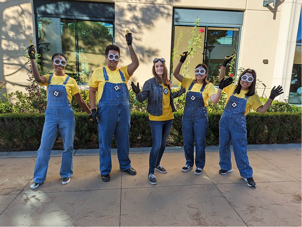 5 people happily posing in costumes outside of a building