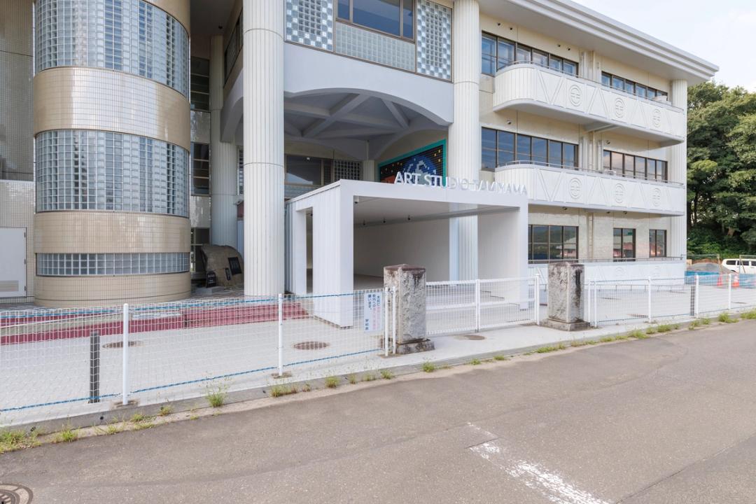 つくばアートスタジオたみやまの外観。旧校舎の正面に白い屋根付きのエントランスが設けられている。