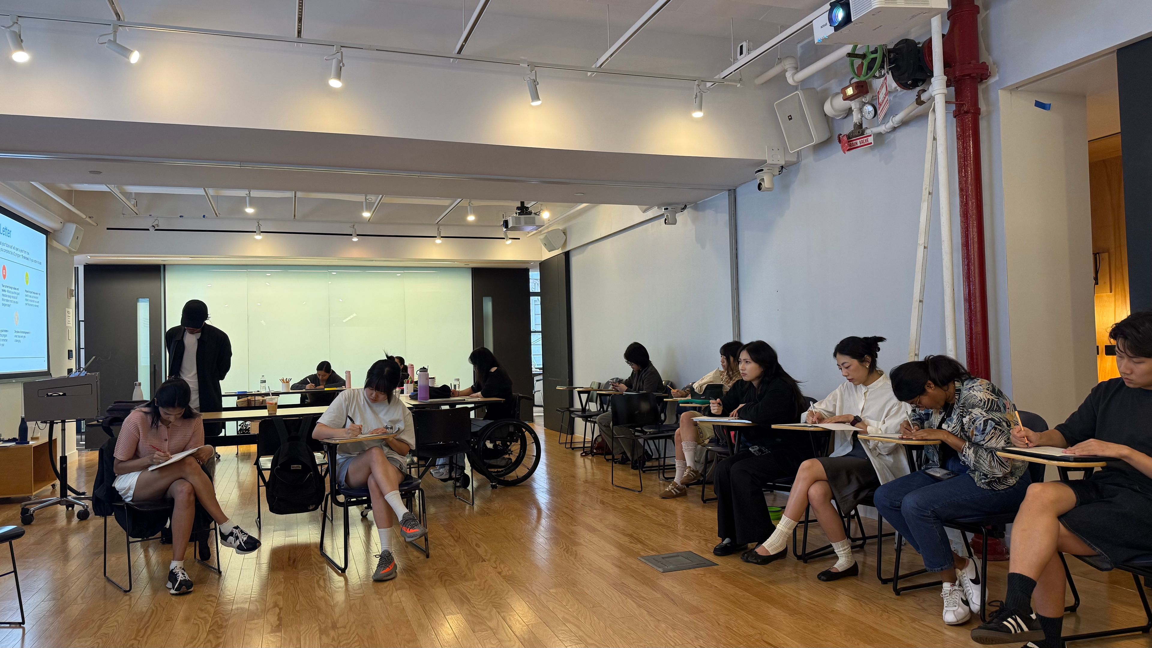 Students writing at their desks in the ixD classroom space. 