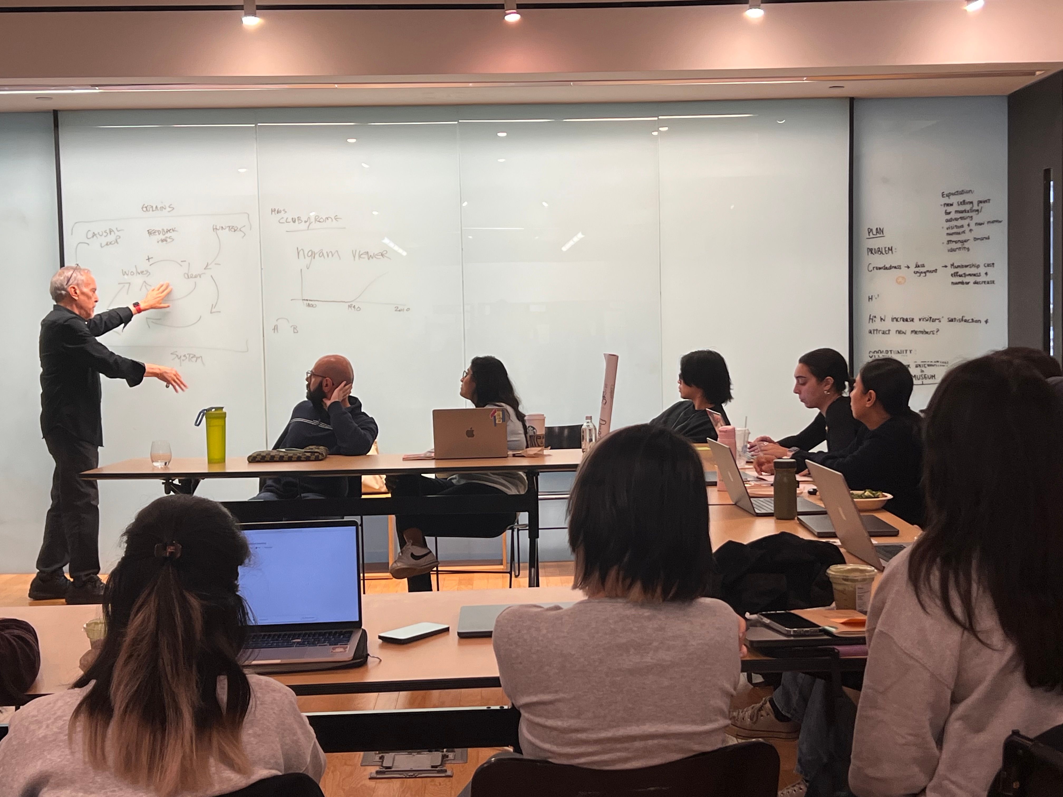 Guest lecture demonstrating concepts written on a whiteboard as students observe.