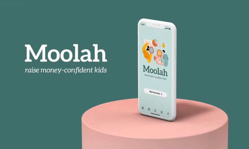 Promotional image for Moolah app. A phone displaying colorful Moolah app interface is placed on a pink podium. Text in white, on dark green background: Moolah Raise Money-Confident Kids. 