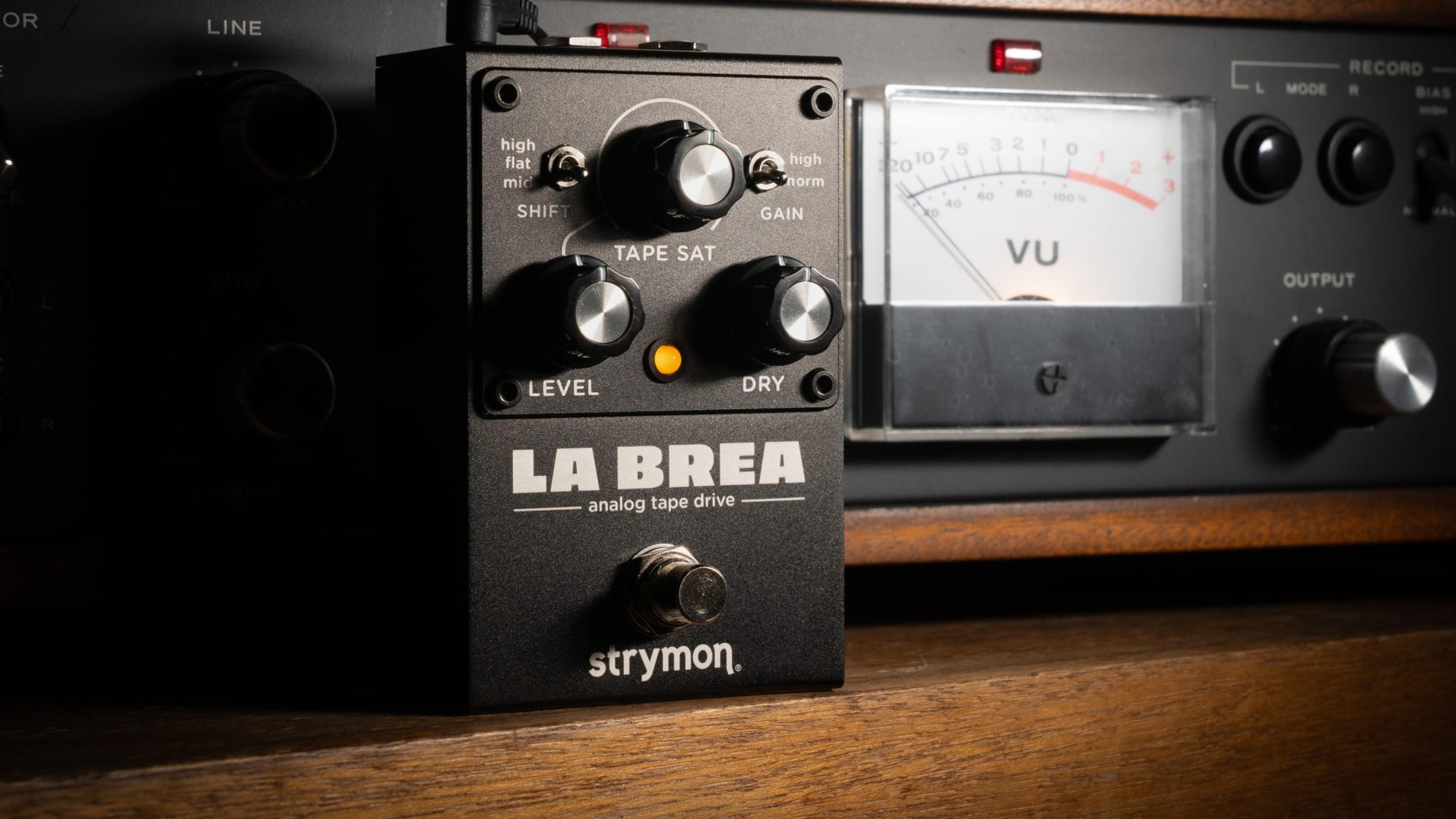 Strymon La Brea analog tape drive on a wooden shelf in front of a TEAC tape machine VU meter
