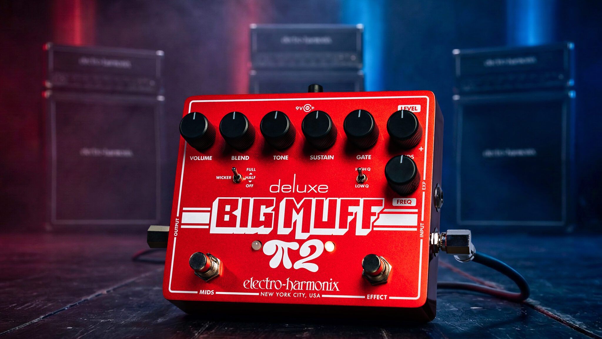 Electro-Harmonix Deluxe Big Muff Pi 2 on a dark stage floor with cables plugged in and amp stacks behind red and blue lights
