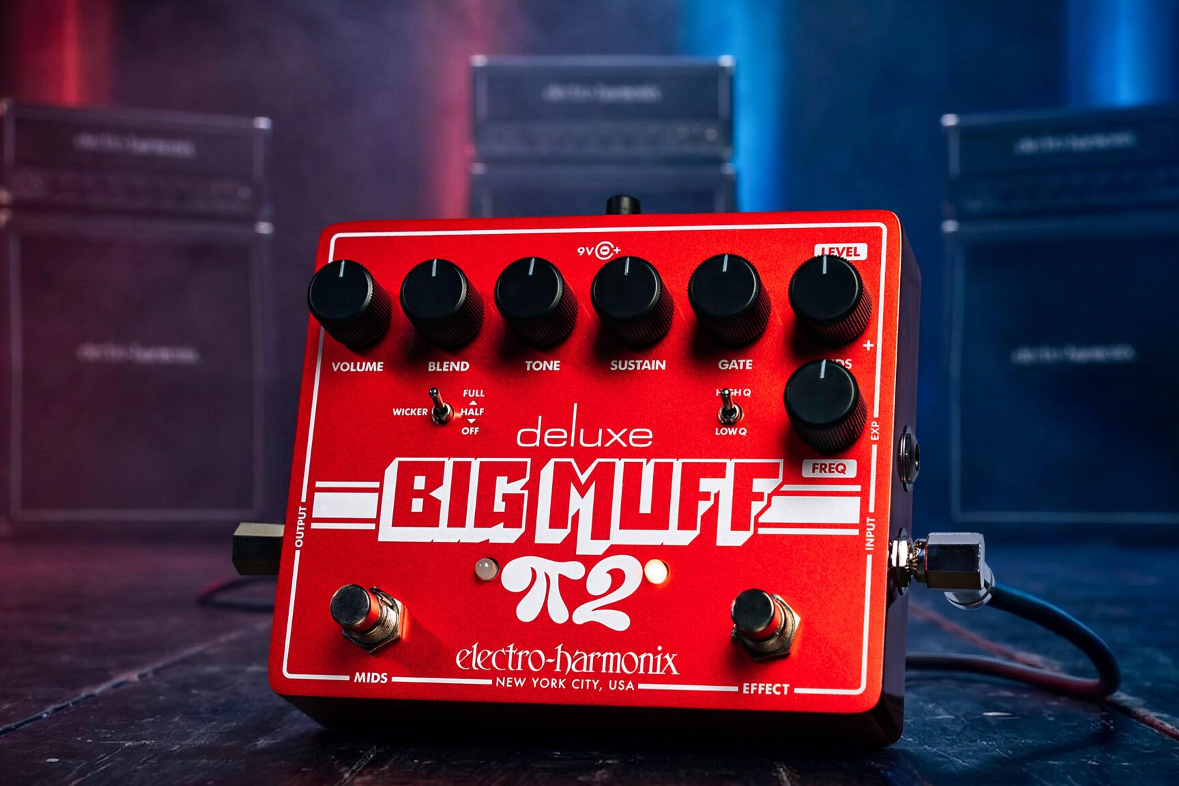 Electro-Harmonix Deluxe Big Muff Pi 2 on a dark stage floor with cables plugged in and amp stacks behind red and blue lights