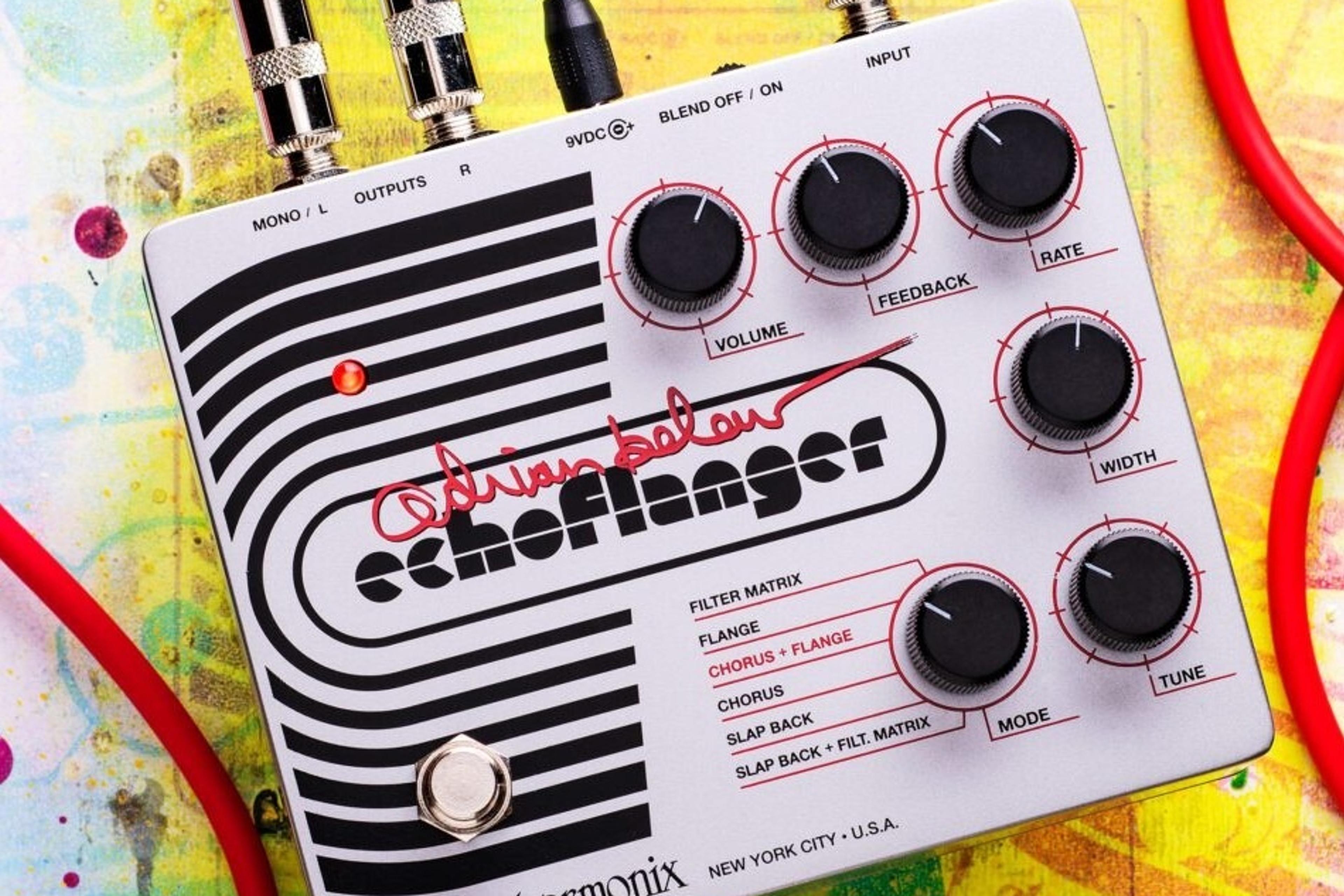 Electro-Harmonix Adrian Belew Echoflanger on a paint-splattered surface with red instrument cables plugged in