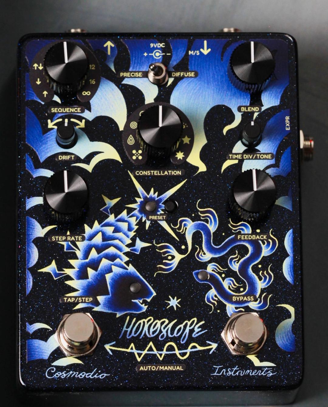Cosmodio Horoscope, top-down, navy enclosure with blue and gold fish and serpent artwork, seven black knobs and two footswitches