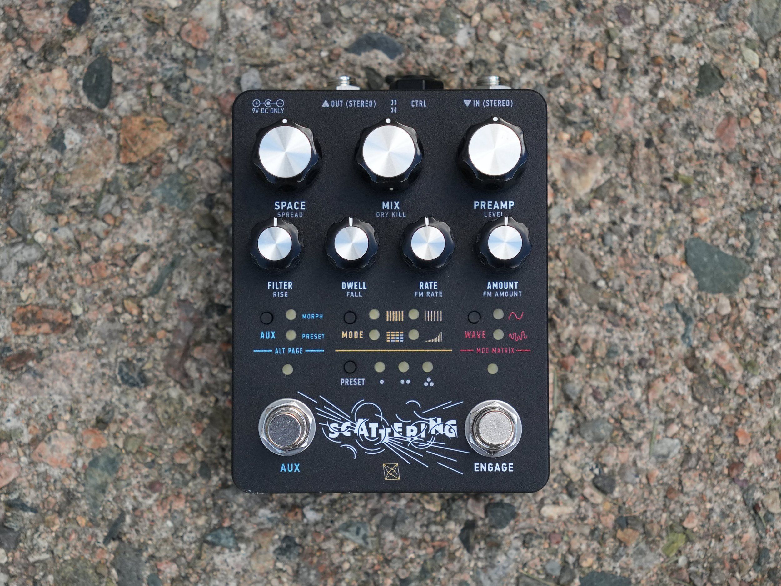 Electronic Audio Experiments Scattering pedal on gravel, top-down hero shot showing knobs, MODE WAVE buttons, and AUX ENGAGE footswitches
