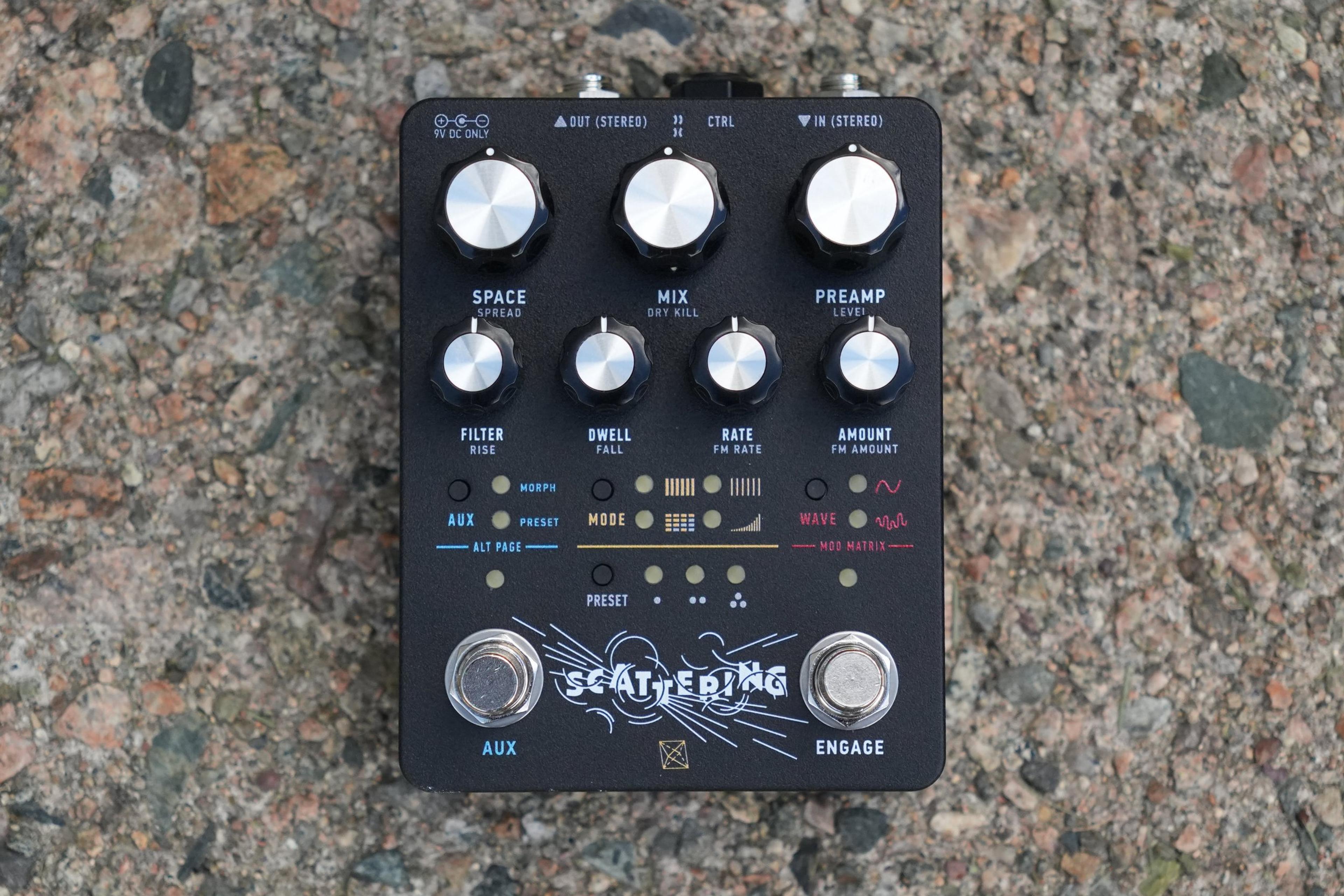 Electronic Audio Experiments Scattering pedal on gravel, top-down hero shot showing knobs, MODE WAVE buttons, and AUX ENGAGE footswitches