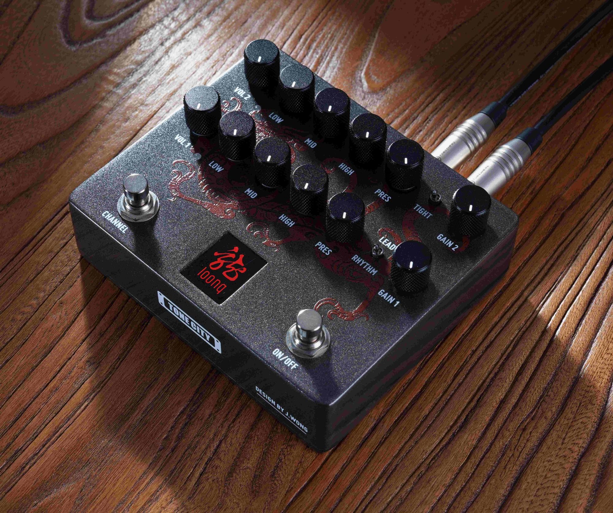 Tone City LOONG on a wooden surface with cables plugged into top jacks, dragon graphic lit