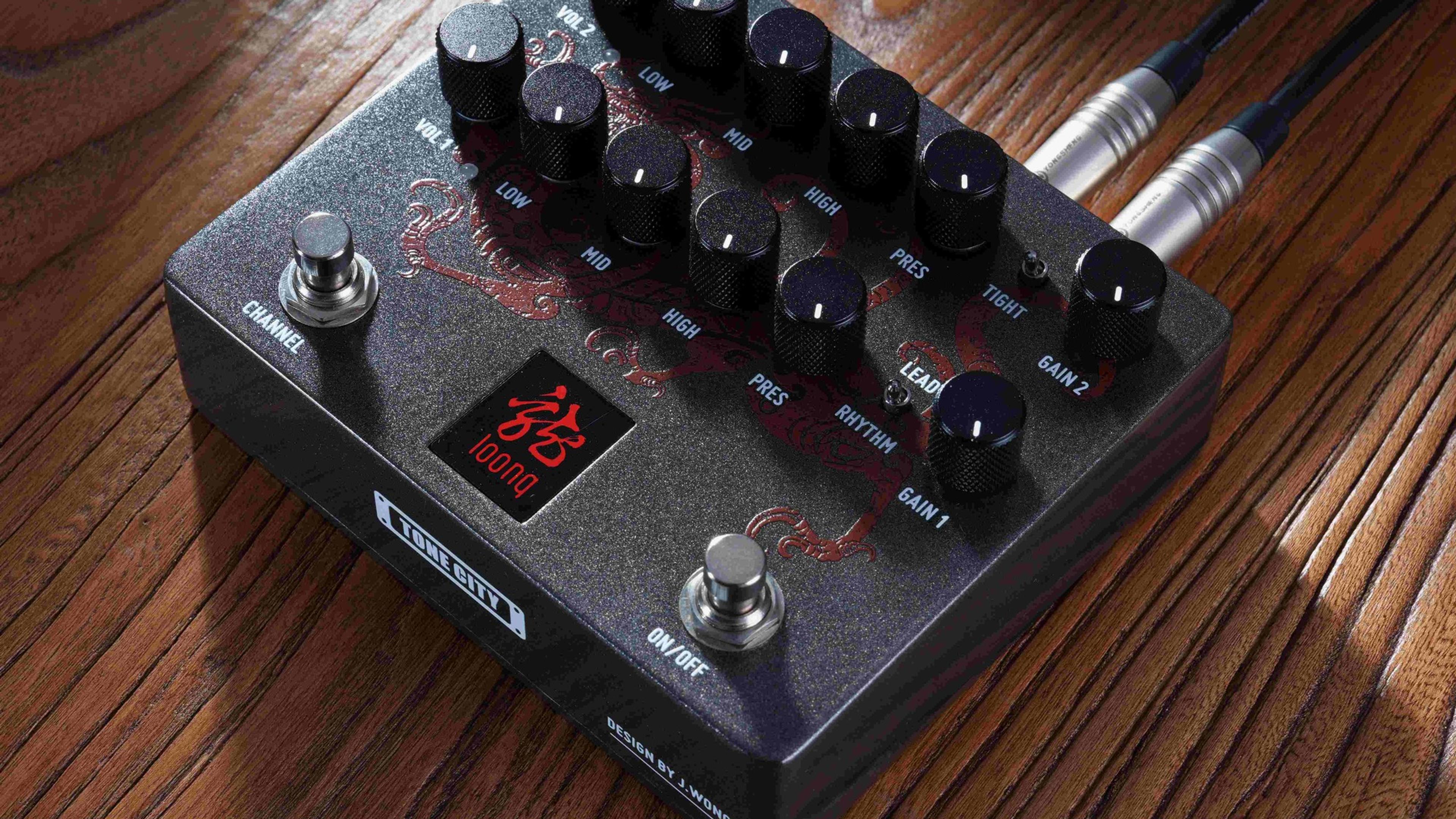 Tone City LOONG on a wooden surface with cables plugged into top jacks, dragon graphic lit