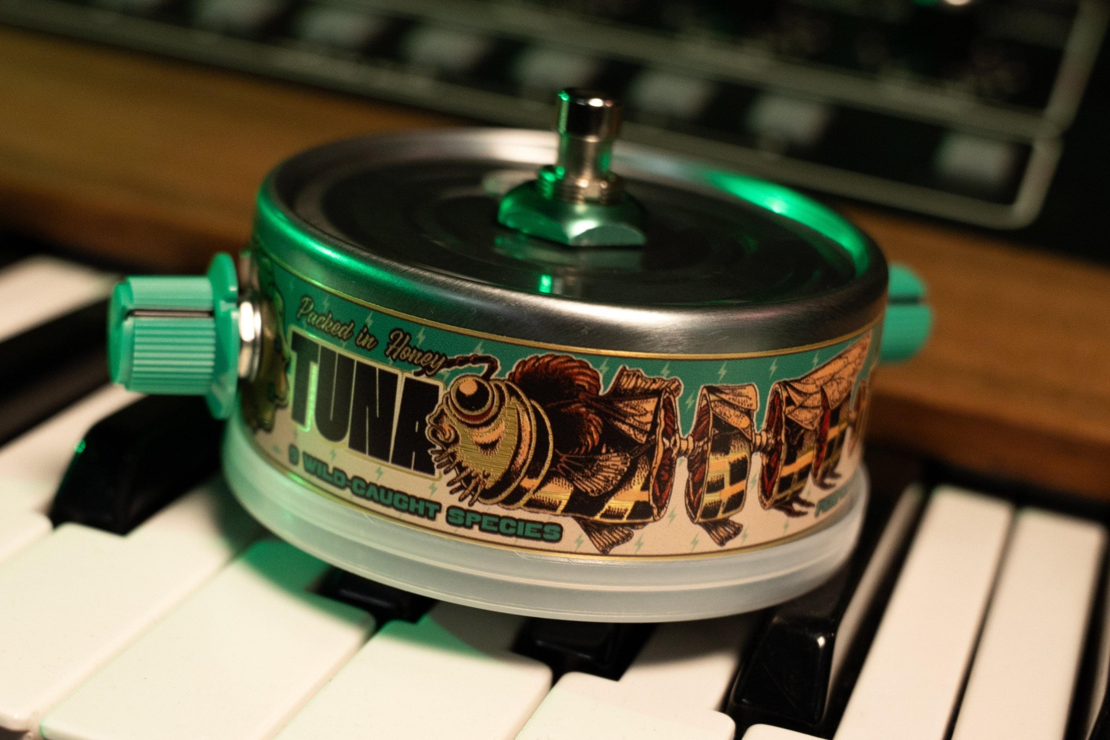 Beetronics Tuna Trem sitting on synth keys under green light, TUNA label with bee artwork and '9 wild-caught species' text