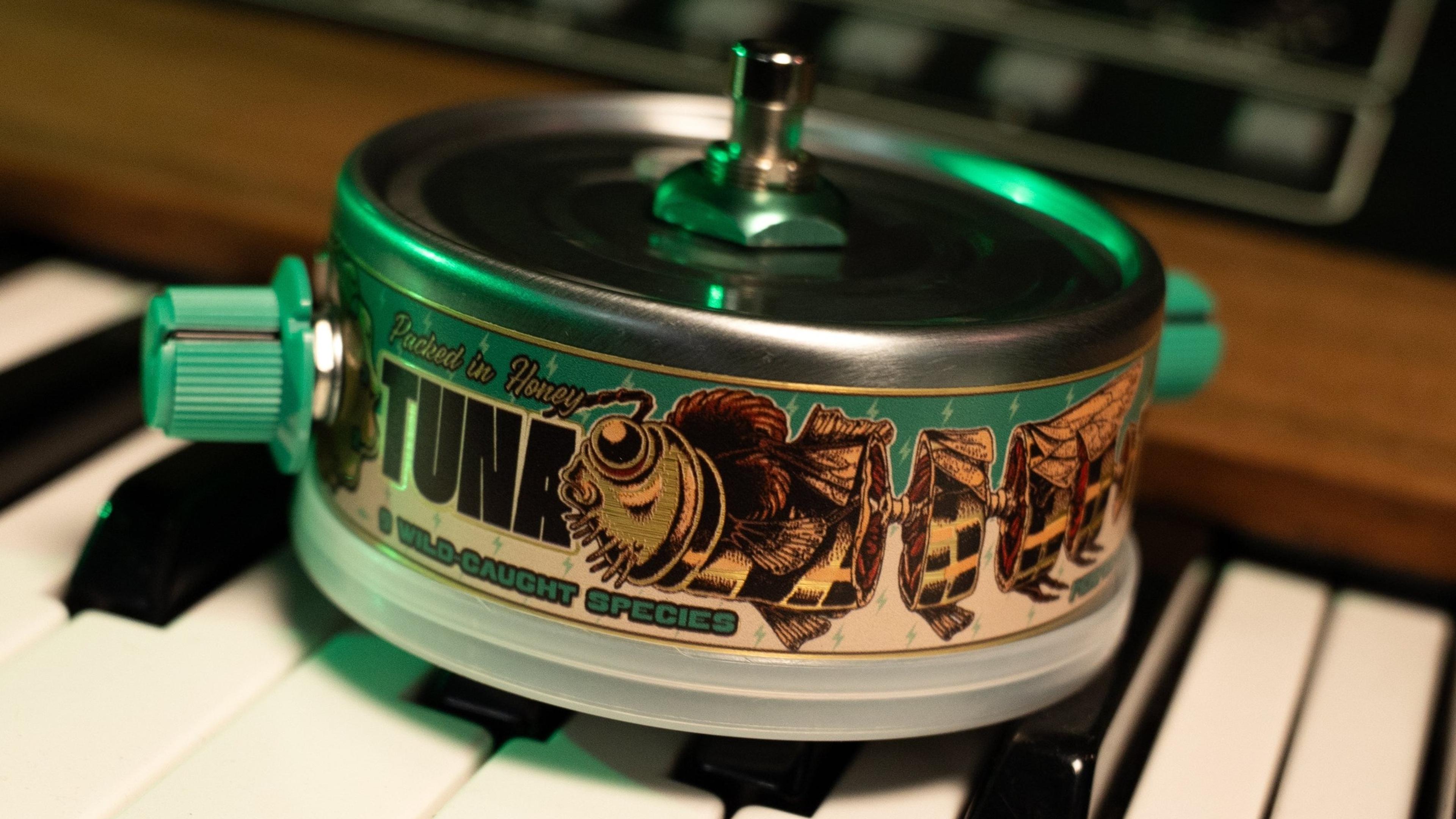 Beetronics Tuna Trem sitting on synth keys under green light, TUNA label with bee artwork and '9 wild-caught species' text