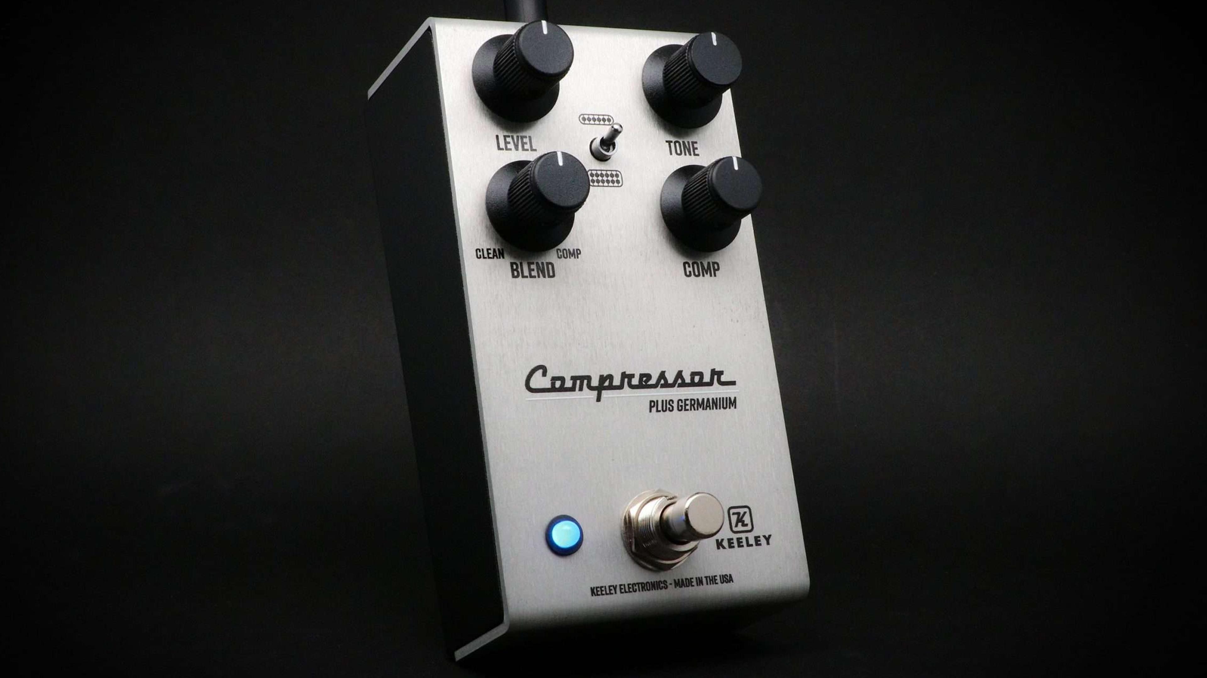 Keeley Compressor Plus Germanium in brushed aluminium, three-quarter view on a black backdrop with the blue status LED lit and Level, Tone, Blend and Comp knobs