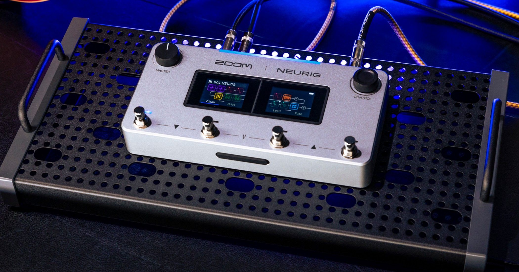 ZOOM NEURIG on a black perforated pedalboard under blue stage light, dual touchscreens lit and cables in the top jacks