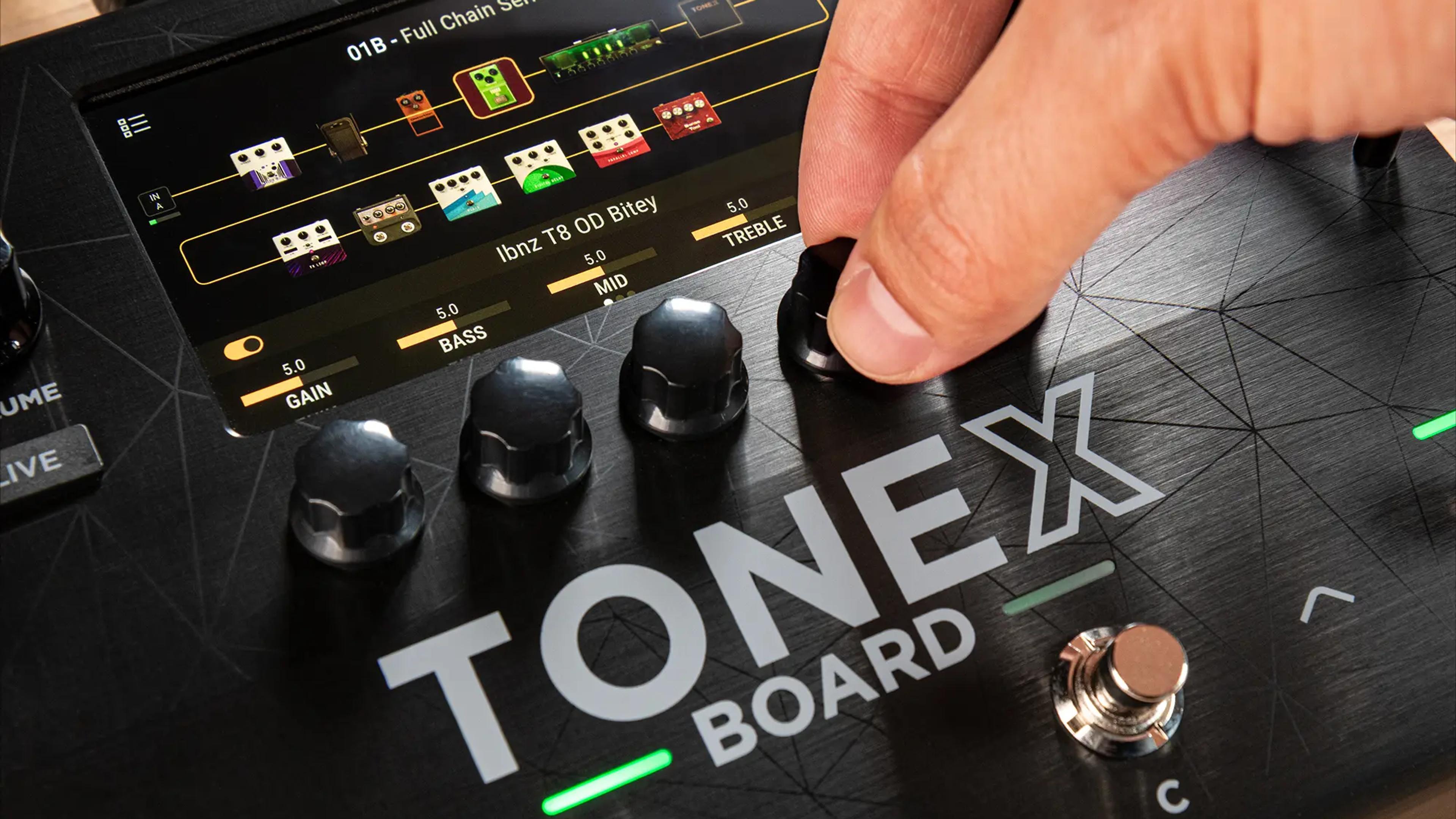 Hand adjusting knobs on an IK Multimedia TONEX Board, colour display showing a full amp and effects chain