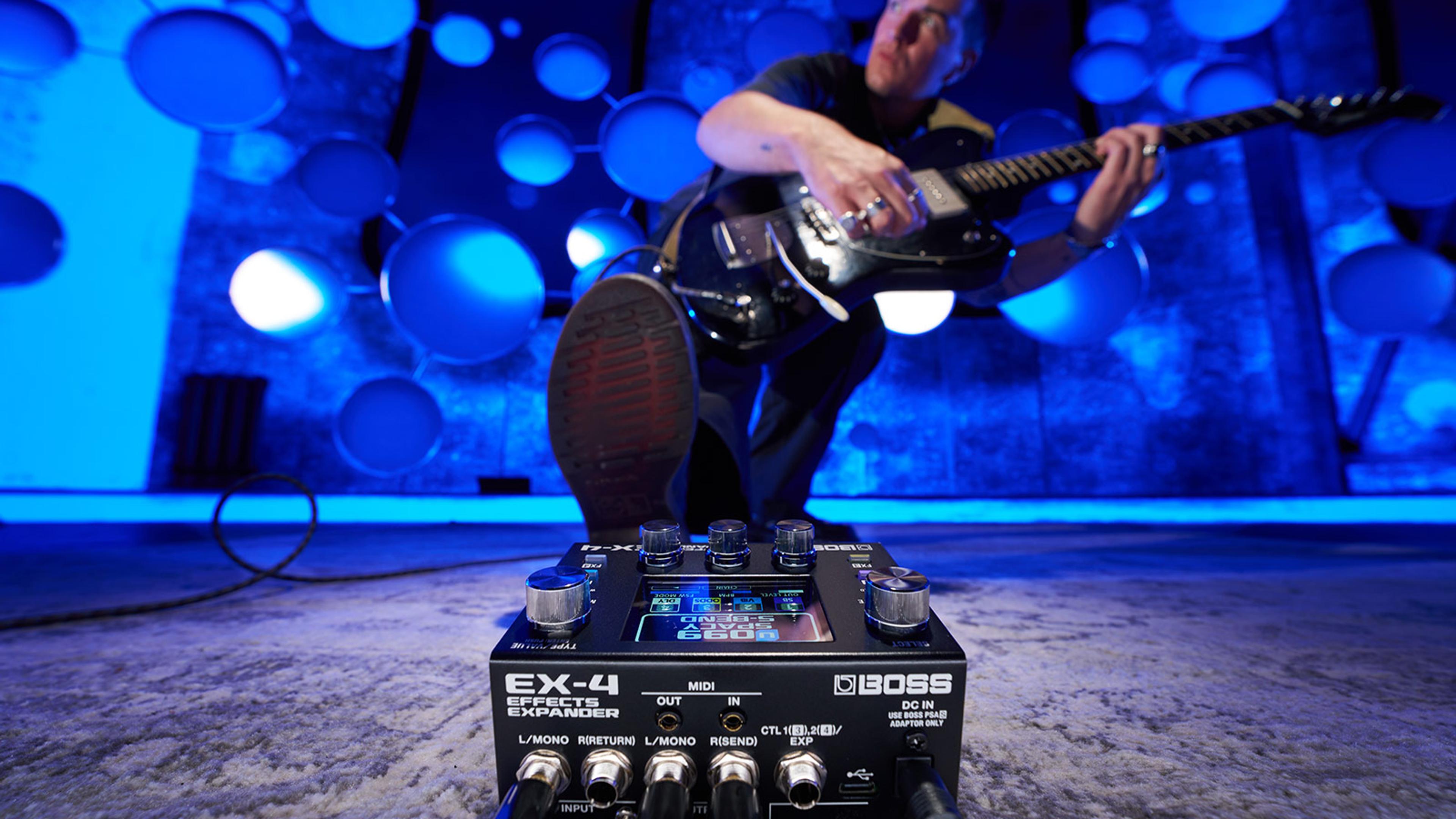 Boss EX-4 Effects Expander on a studio floor with a guitarist playing in a blue-lit room behind it