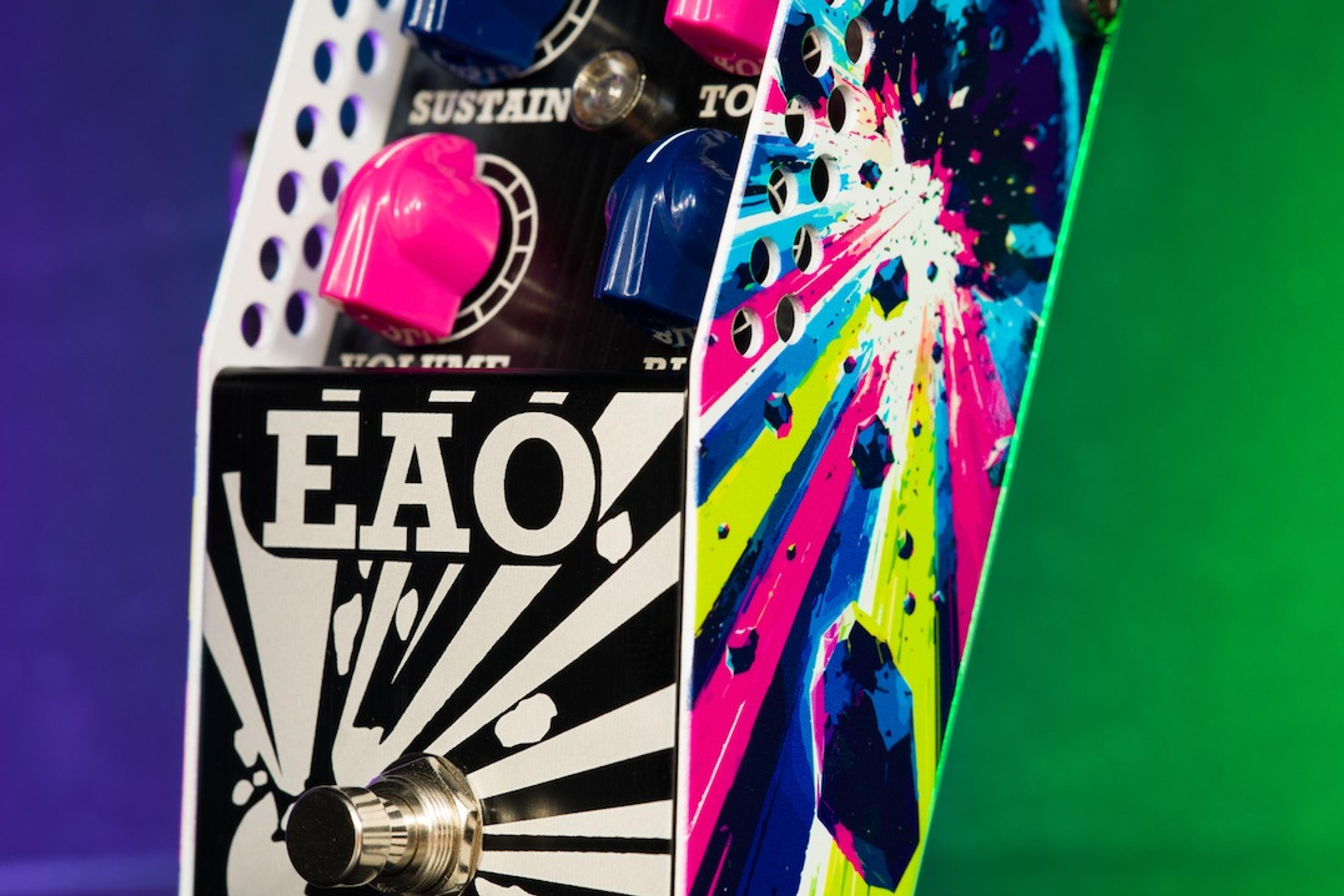 ThorpyFX EAO fuzz at an angle on a purple and green lit backdrop, showing pink and blue knobs and the explosion artwork on its side panel