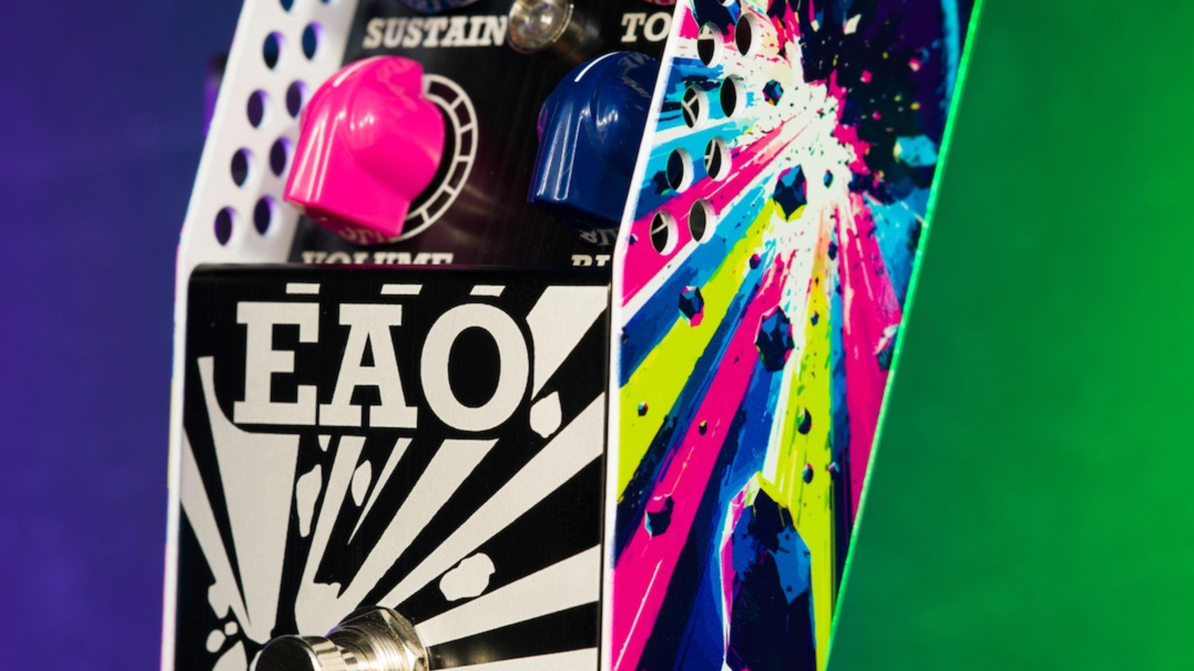 ThorpyFX EAO fuzz at an angle on a purple and green lit backdrop, showing pink and blue knobs and the explosion artwork on its side panel