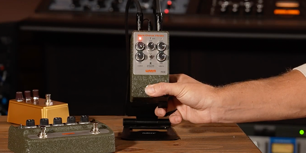 Warm Audio WA-C1 Mod chorus vibrato pedal on a studio stand with a hand pressing the footswitch