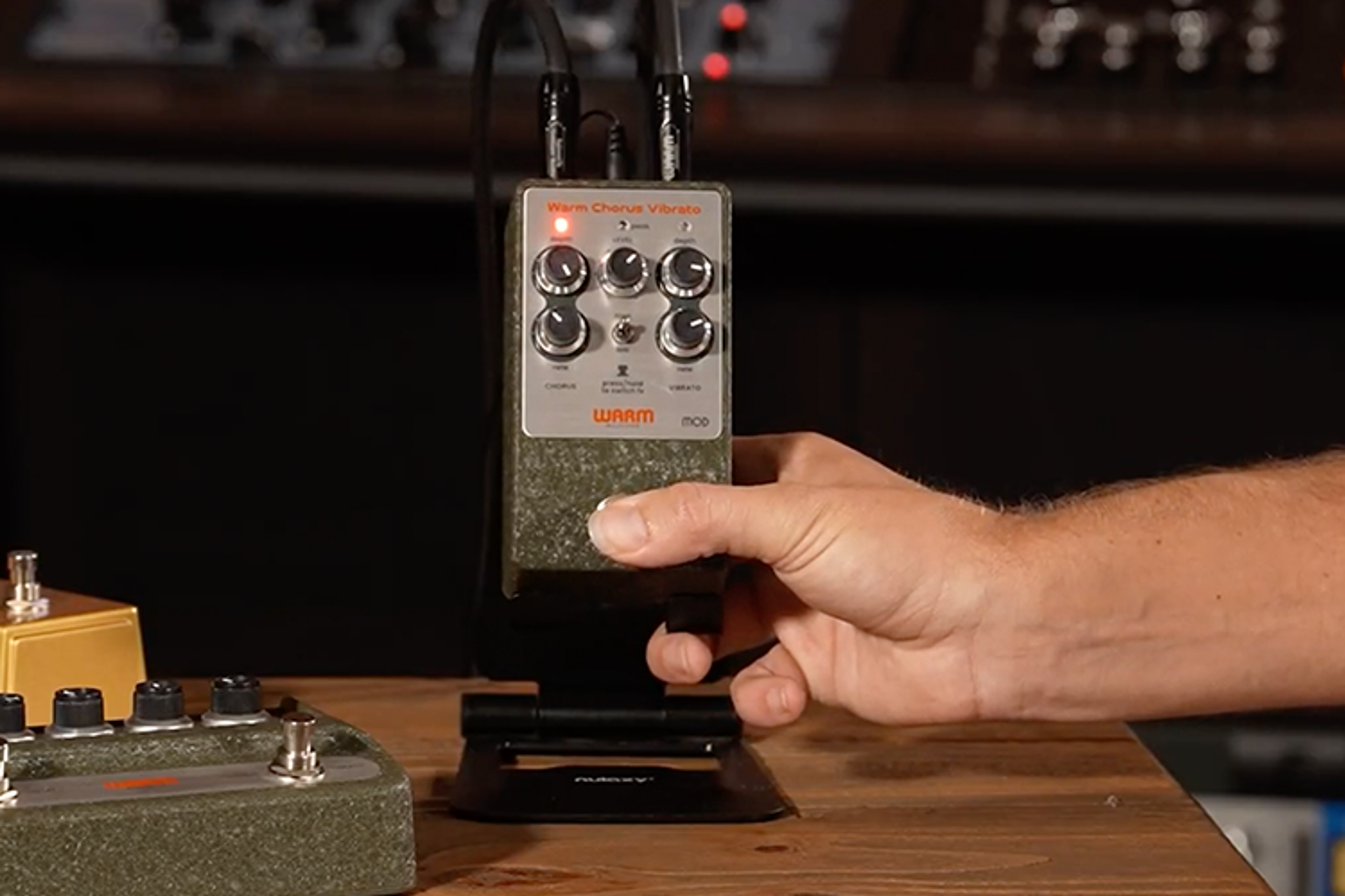 Warm Audio WA-C1 Mod chorus vibrato pedal on a studio stand with a hand pressing the footswitch