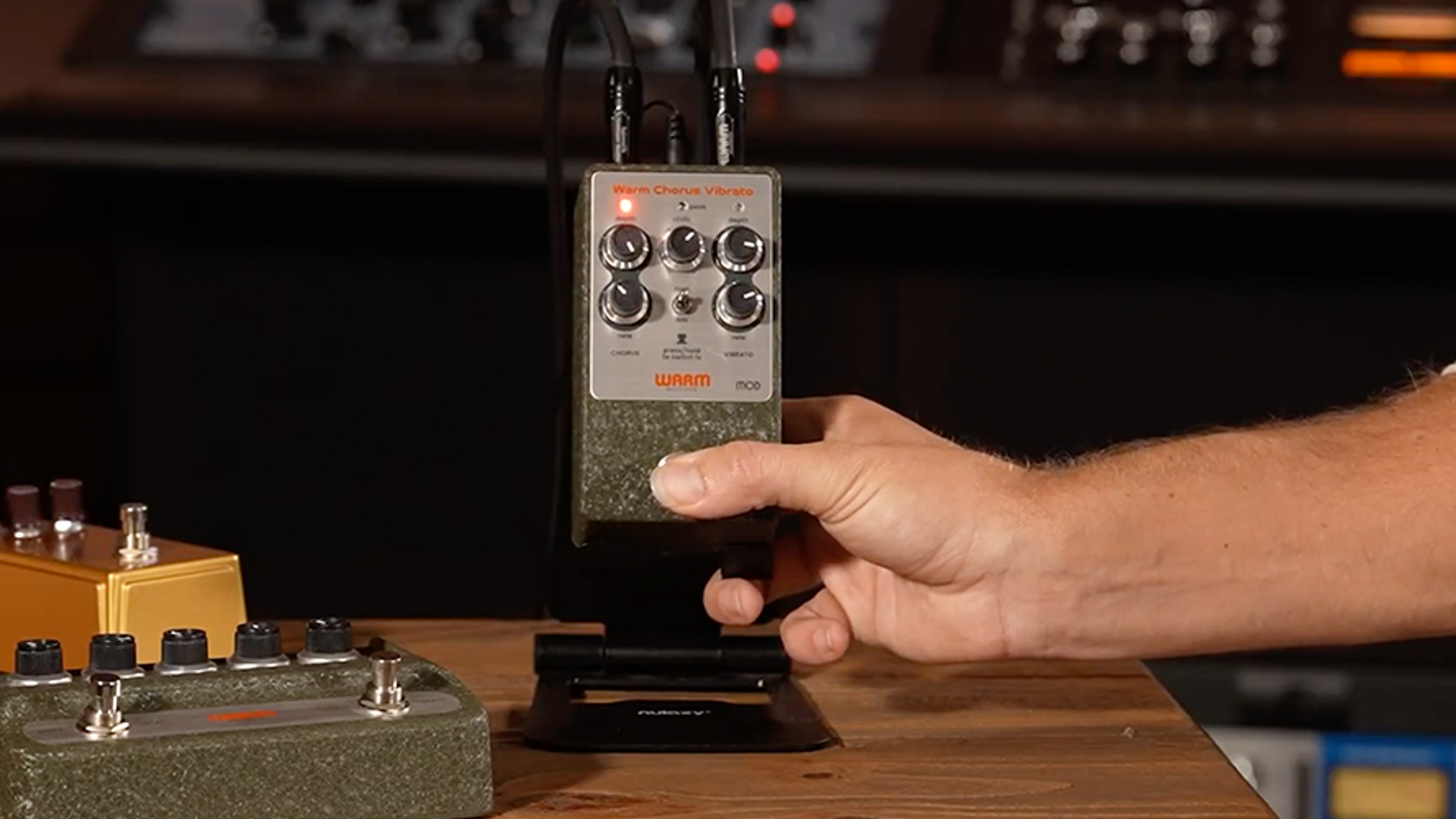 Warm Audio WA-C1 Mod chorus vibrato pedal on a studio stand with a hand pressing the footswitch