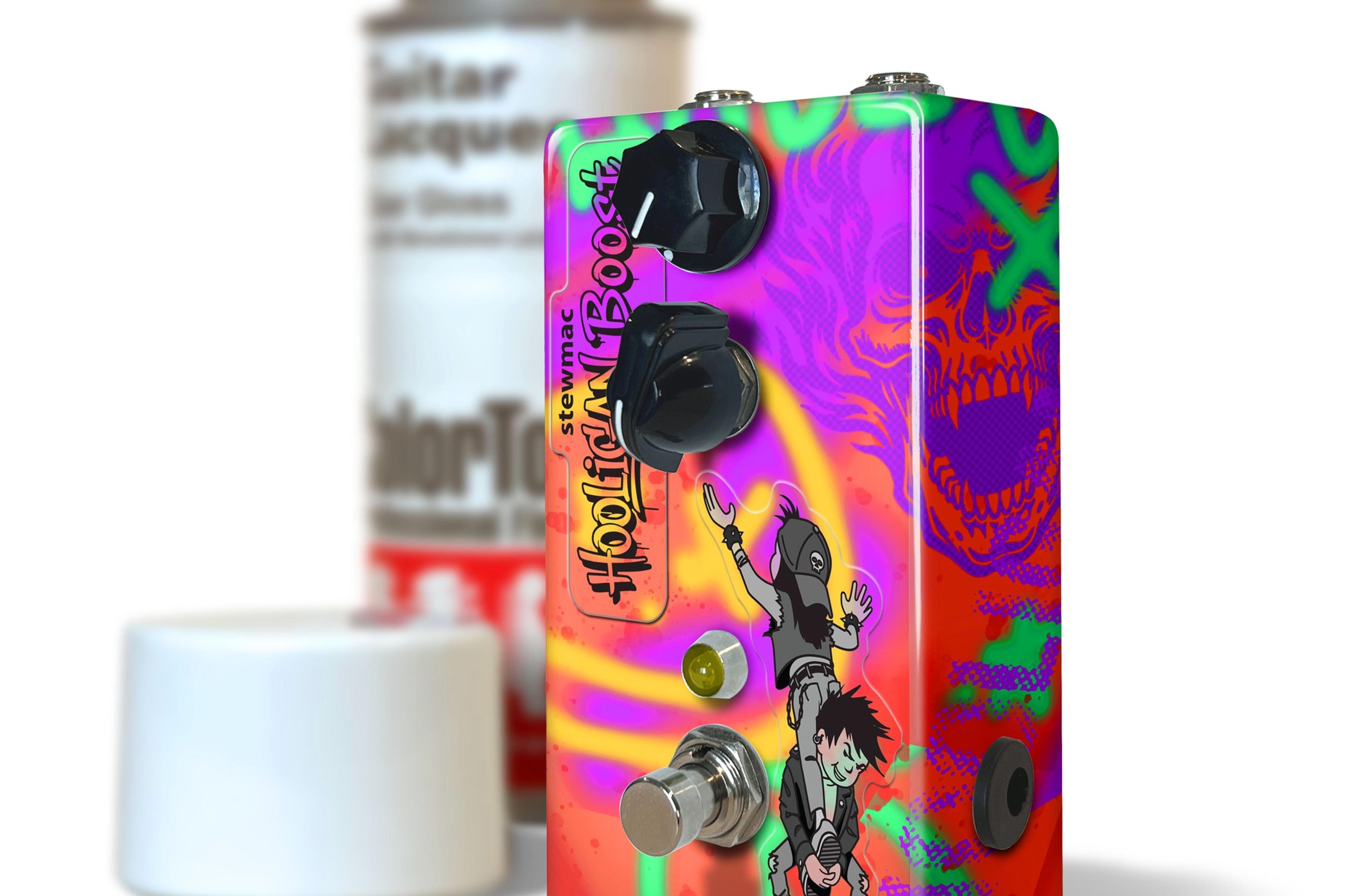 StewMac Hooligan Boost custom-painted enclosure next to a ColorTone spray can, graffiti graphics and skull side art