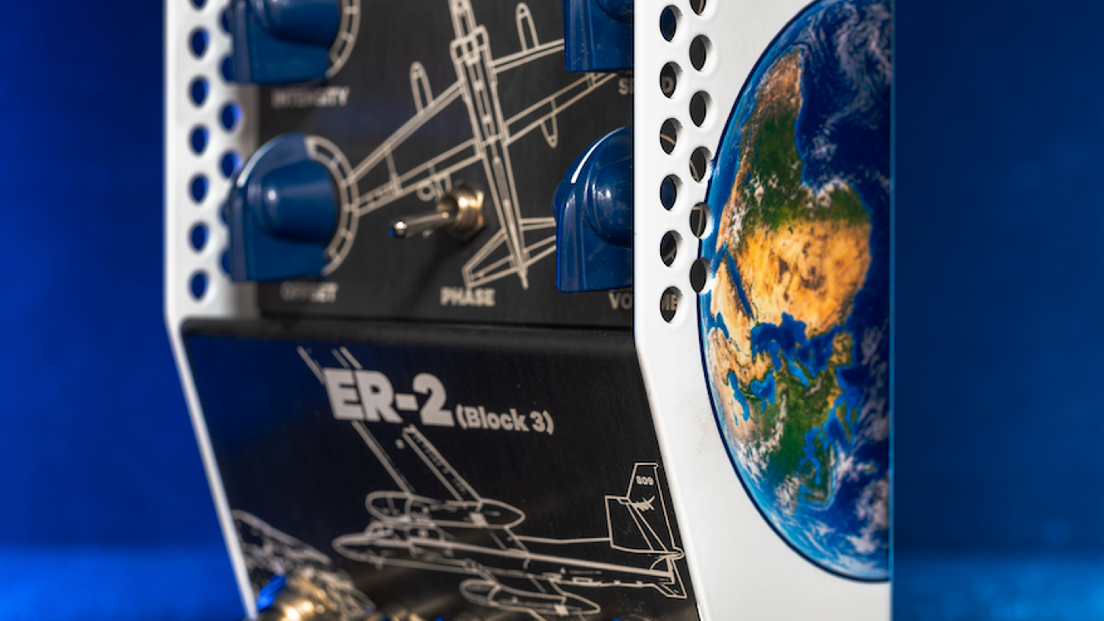 ThorpyFX ER-2 Block 3 seen from the side in blue light, black panel with blue knobs and aircraft line art, a Phase toggle and an Earth graphic on the white side panel