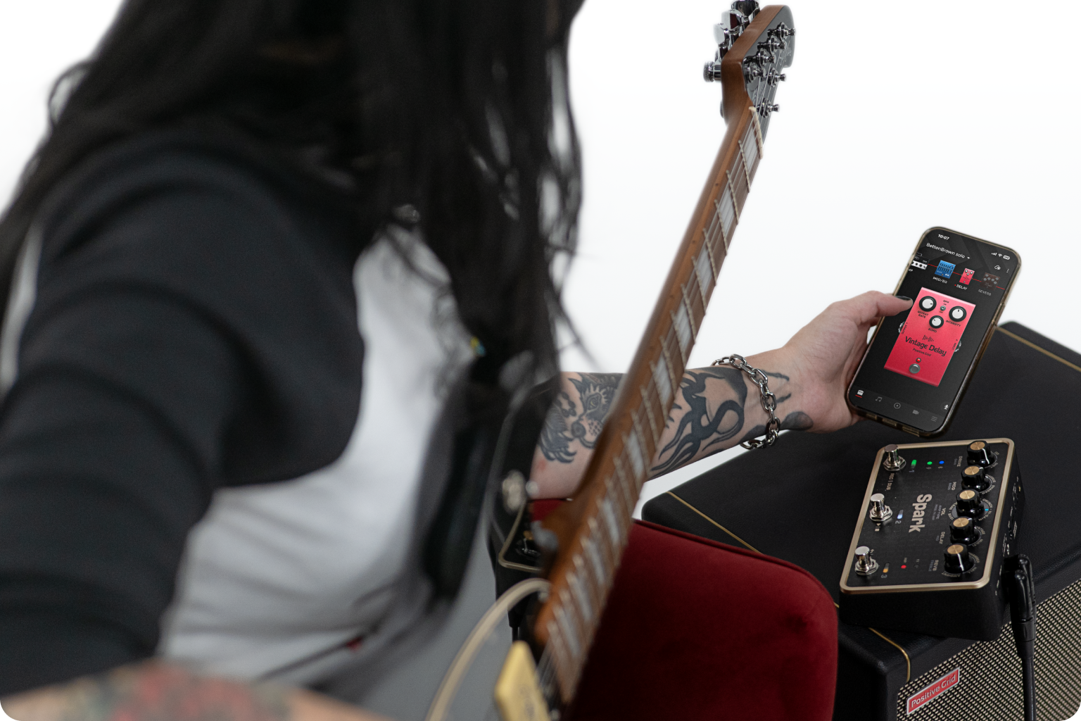Guitarist using the Positive Grid Spark PEDAL with the companion app, pedal resting on a Positive Grid amp