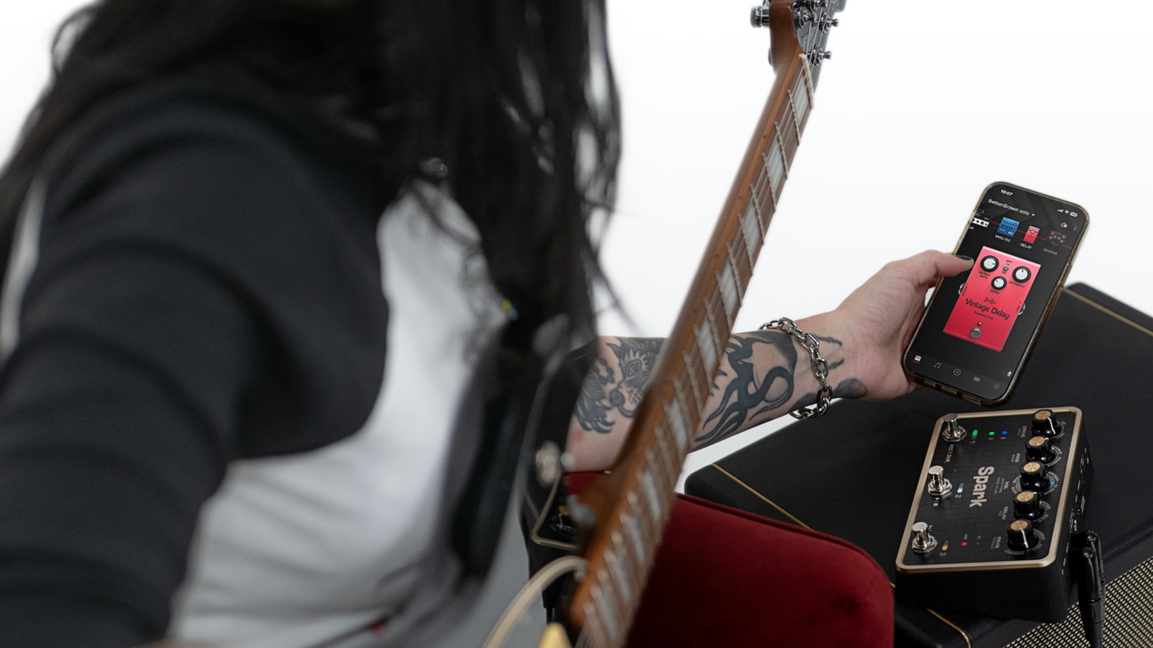 Guitarist using the Positive Grid Spark PEDAL with the companion app, pedal resting on a Positive Grid amp