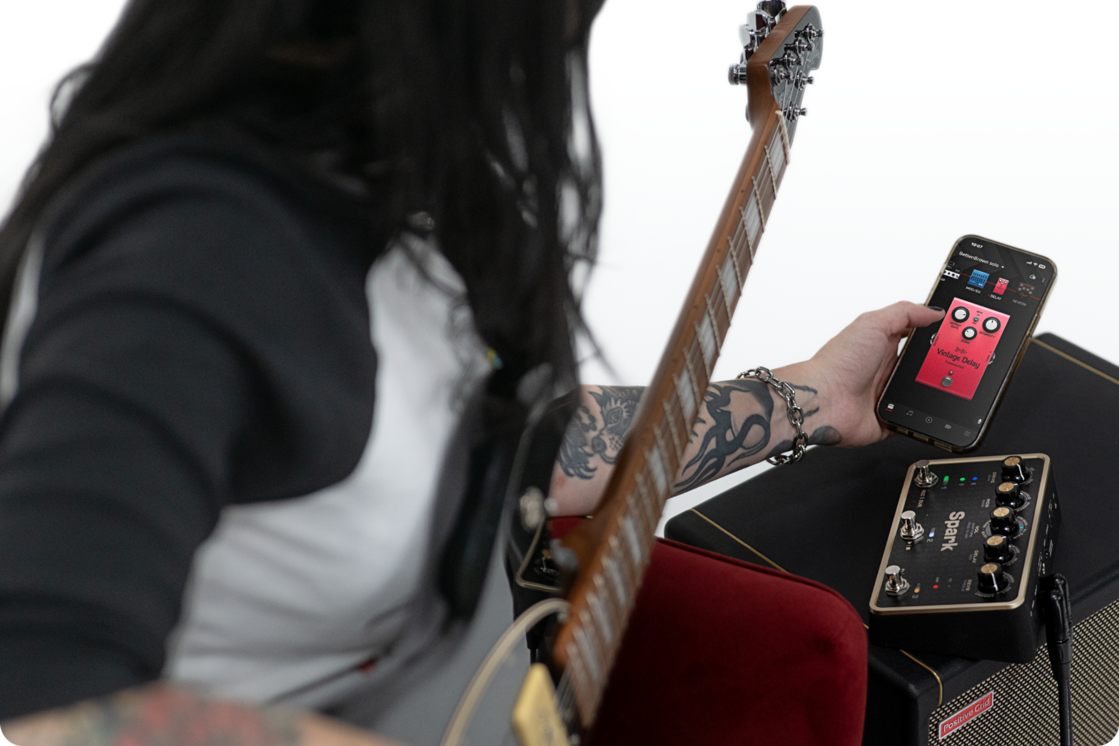 Guitarist using the Positive Grid Spark PEDAL with the companion app, pedal resting on a Positive Grid amp