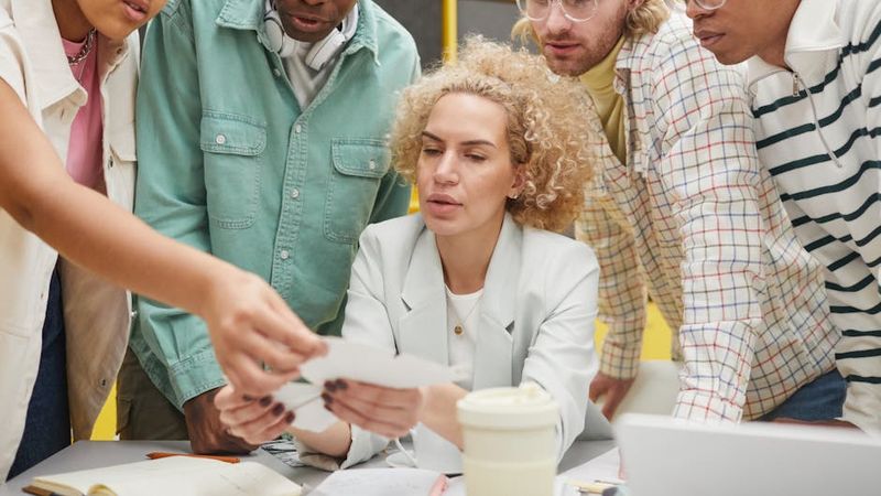 Gruppe unterschiedlicher Erwachsener, die in einem modernen Arbeitsbereich an einem Projekt zusammenarbeiten.