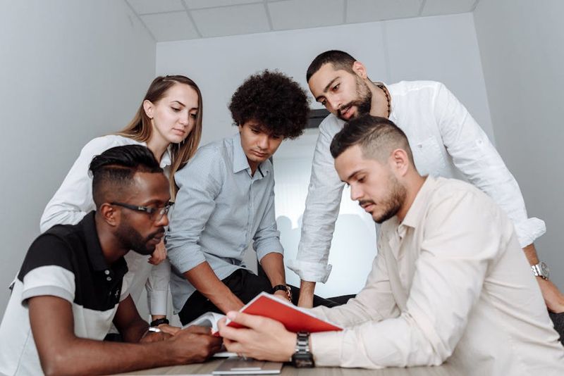 Uma equipe multicultural engajada em uma reunião de escritório colaborativa, discutindo ideias em torno de uma mesa.