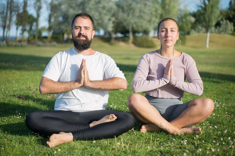 Meditazione serena all'aperto con una coppia seduta a gambe incrociate in un parco portoghese.