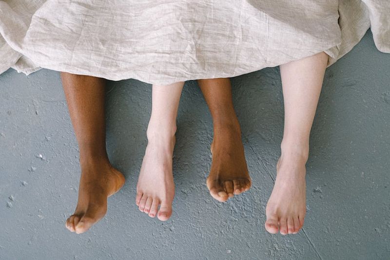 Feet of an interracial couple lying on the floor, symbolizing love and diversity.