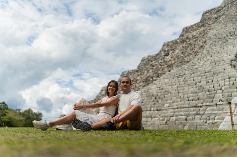Glückliches Paar sitzt in Yucatan in der Nähe einer alten Maya-Pyramide und genießt einen sonnigen Tag im Freien.