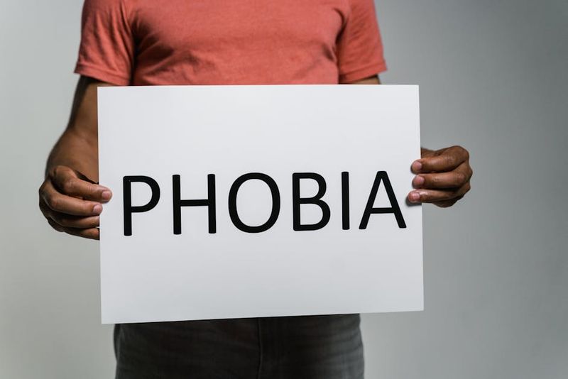 Adulto segurando uma placa com a palavra 'Fobia' para transmitir conceitos de medo e ansiedade.