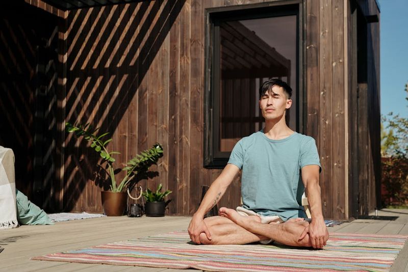 Man meditating outdoors with closed eyes, enjoying a peaceful moment on a sunny day.