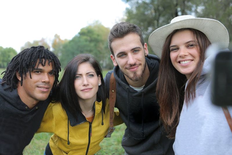 Eine vielfältige Gruppe von Freunden genießt einen lustigen Tag im Freien und macht ein Selfie im Park.