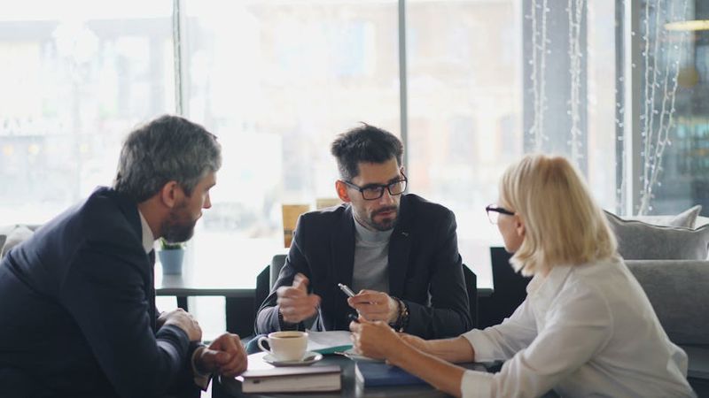 Profesionales de negocios en una reunión en un café, compartiendo ideas y discutiendo.