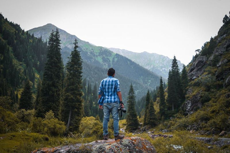Un fotógrafo se encuentra en medio del sereno paisaje montañoso en Ak-Talaa, Kirguistán.