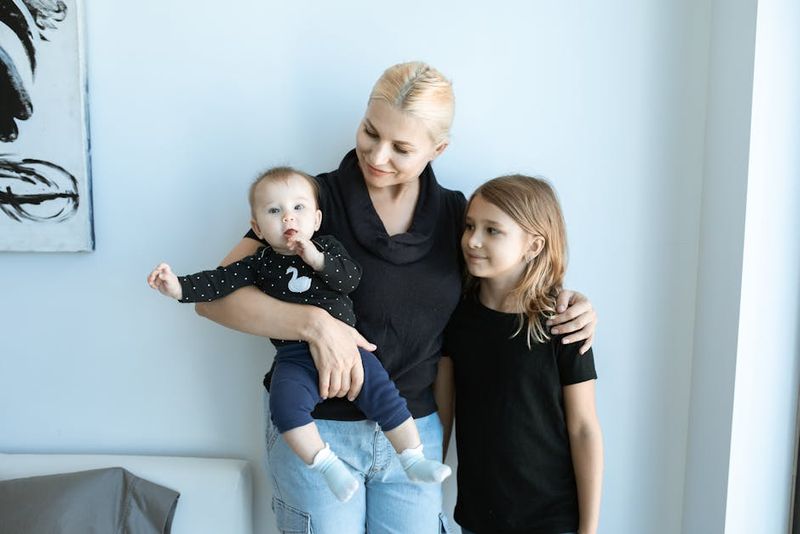 Smiling mother with baby and child in a loving family embrace at home.