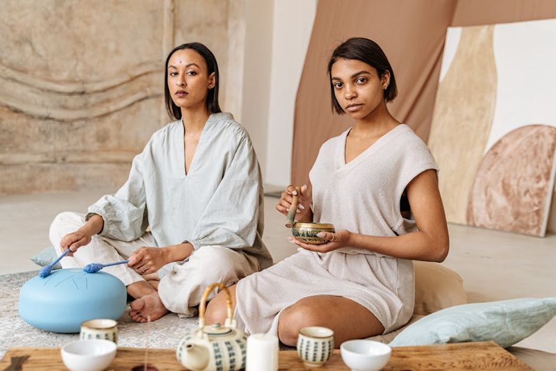 Zwei Frauen meditieren drinnen mit einer Hang Drum und einer Klangschale.