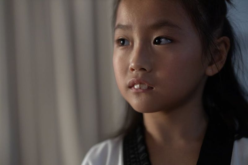 Close-up portrait of a young girl in a martial arts uniform, looking thoughtful.
