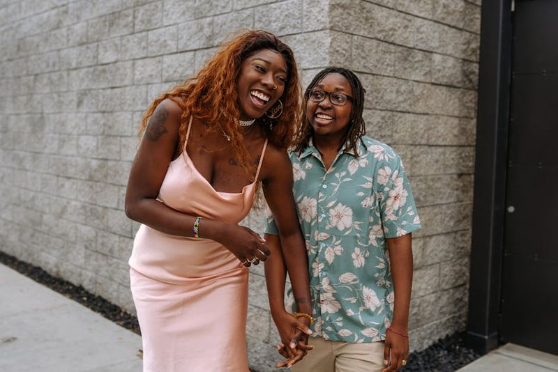 Happy couple standing outdoors, laughing and holding hands, showcasing love and joy.